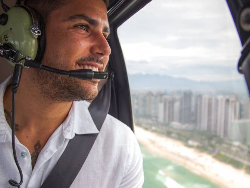 Homem sorrindo durante passeio de helicóptero.