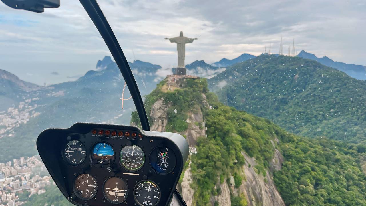 Voo de helicóptero com o Cristo Redentor ao fundo.